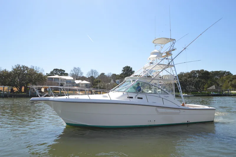 Side Chick Yacht Photos Pics 2002 Rampage 38 Express boat cruising on a sunny day near waterfront homes.