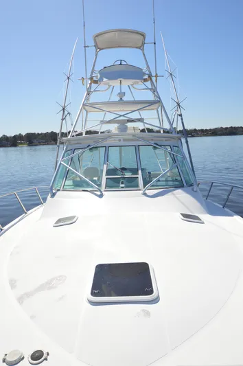 Side Chick Yacht Photos Pics 2002 Rampage 38 Express boat on calm water, featuring a tall tower and clear blue sky.