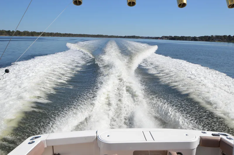 Side Chick Yacht Photos Pics Wake trail behind a 2002 Rampage 38 Express boat on a clear, sunny day.