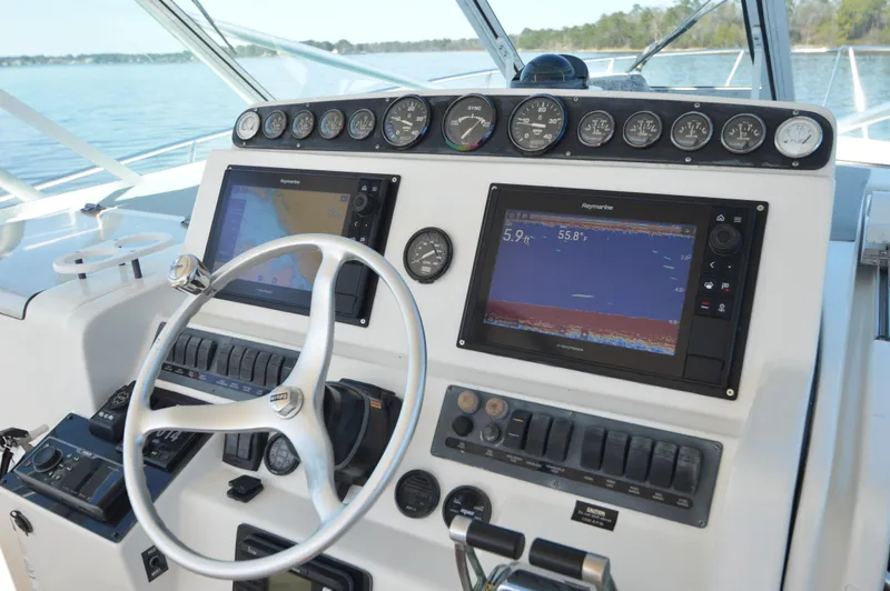 Side Chick Yacht Photos Pics Control panel of a 2002 Rampage 38 Express boat with navigation screens and gauges.