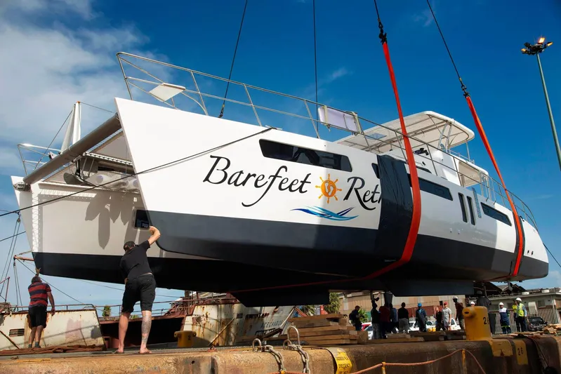 Barefeet Retreat Yacht Photos Pics 2020 Royal Cape Catamarans Majestic 570 being lifted at a dock, clear blue sky.