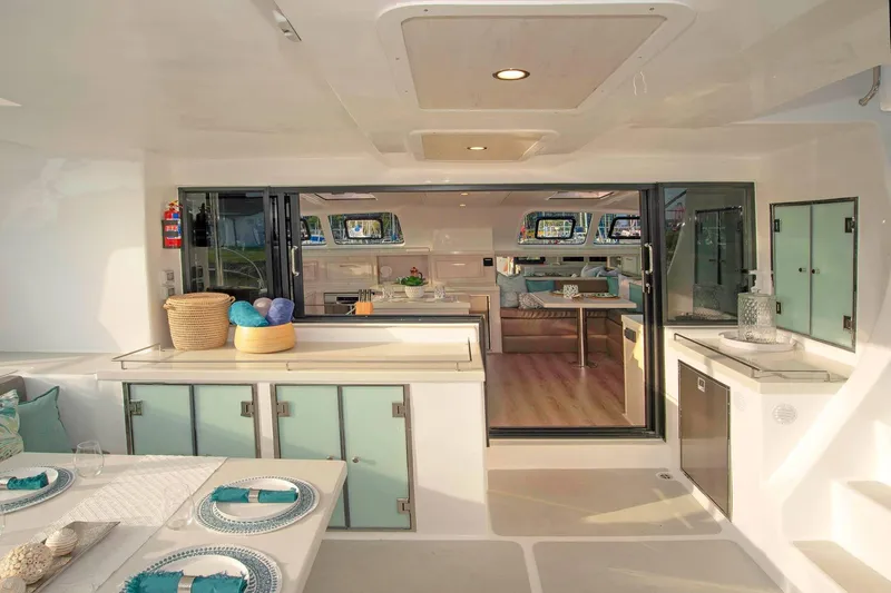 Barefeet Retreat Yacht Photos Pics Luxurious interior of 2020 Royal Cape Catamarans Majestic 570, featuring elegant dining and kitchen area.