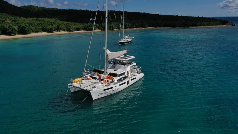 Barefeet Retreat Yacht Photos Pics 2020 Royal Cape Catamarans Majestic 570 anchored in clear blue waters near a lush coastline.