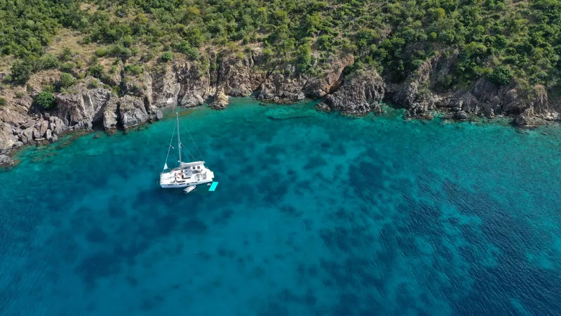 Barefeet Retreat Yacht Photos Pics Aerial view of 2020 Royal Cape Catamarans Majestic 570 anchored near rocky coastline.