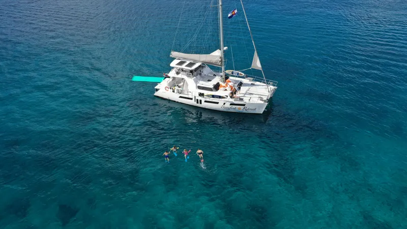 Barefeet Retreat Yacht Photos Pics 2020 Royal Cape Catamarans Majestic 570 anchored, people swimming in clear blue ocean.