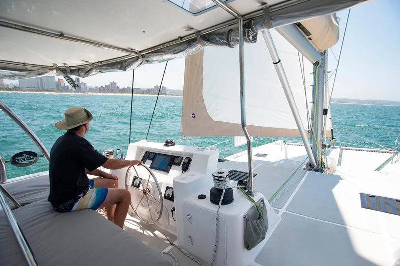 Barefeet Retreat Yacht Photos Pics Man steering 2020 Royal Cape Catamarans Majestic 570 on open sea.