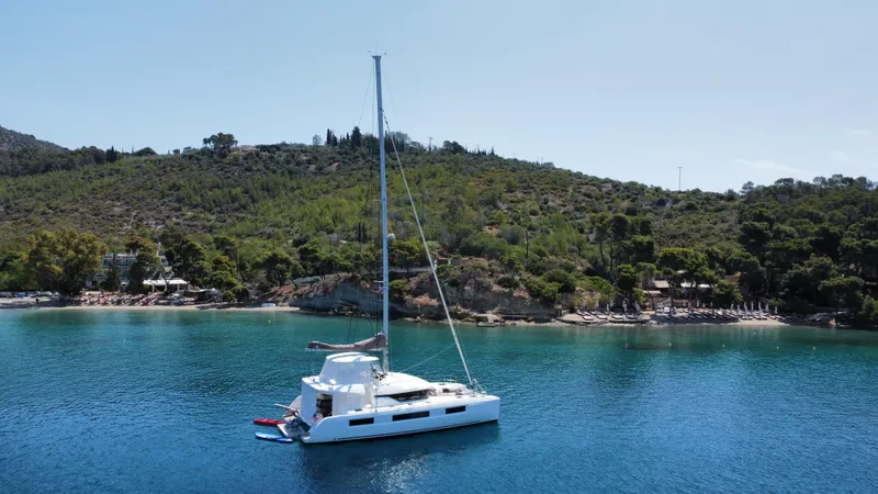  Yacht Photos Pics Lagoon 50 catamaran sailing in clear blue waters near a lush green island, 2021 model.