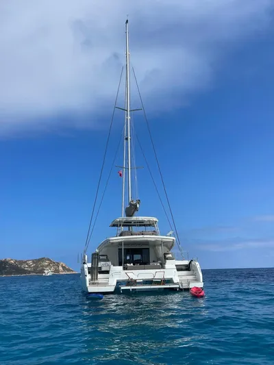  Yacht Photos Pics 2021 Lagoon 50 catamaran anchored in clear blue ocean with scenic coastline.