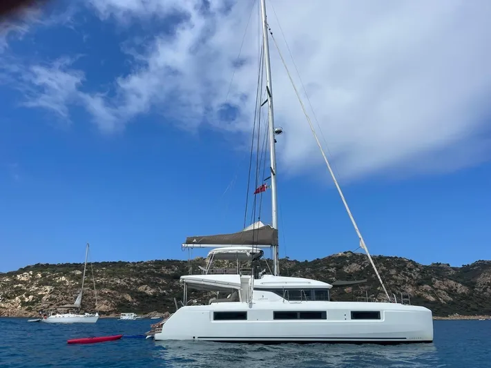  Yacht Photos Pics 2021 Lagoon 50 catamaran anchored in scenic coastal waters under a clear blue sky.