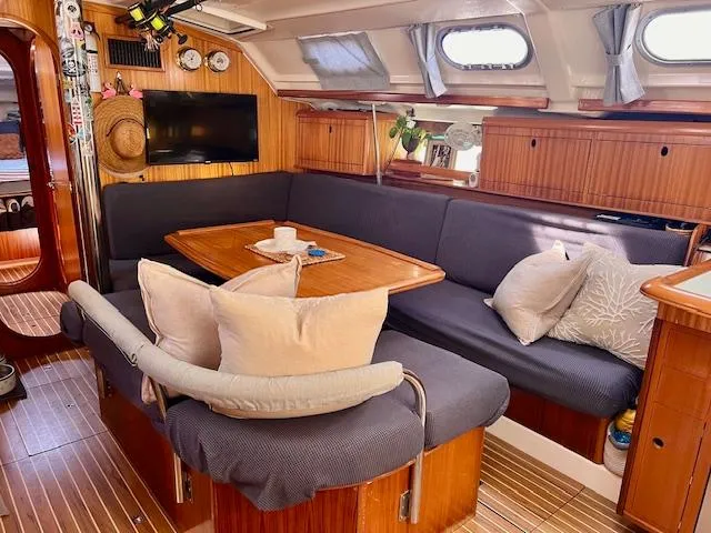 Mockingbird Yacht Photos Pics Cozy interior of 2001 Dufour Gib'Sea 43 sailboat with wooden furnishings and cushioned seating.