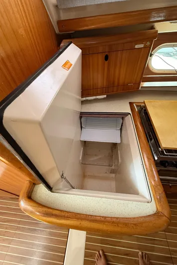 Mockingbird Yacht Photos Pics Open refrigerator in 2001 Dufour Gib'Sea 43 yacht kitchen interior, wooden cabinetry, and flooring.