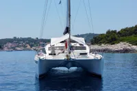 Catamaran Privilege 515, 2010 model, anchored in serene coastal waters with scenic backdrop.