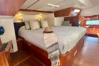 Luxurious cabin interior of 2010 Privilege 515 yacht with cozy bed and elegant wood finish.