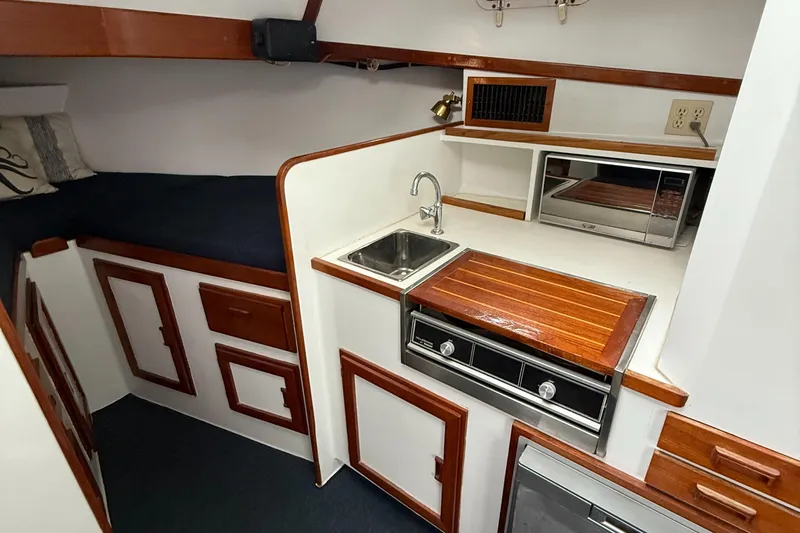 Salty Dog Yacht Photos Pics Compact boat kitchen with wood accents, sink, stove, and microwave in a Young Brothers 38, 1993 model.