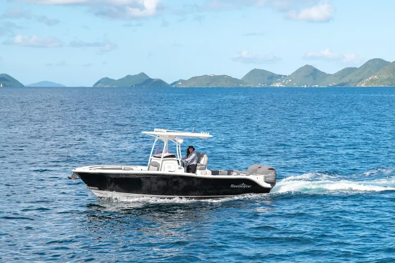  Yacht Photos Pics A NauticStar boat cruising on blue ocean waters with distant green hills.