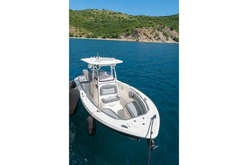  Yacht Photos Pics Small boat docked in clear blue water near a lush, green hillside.