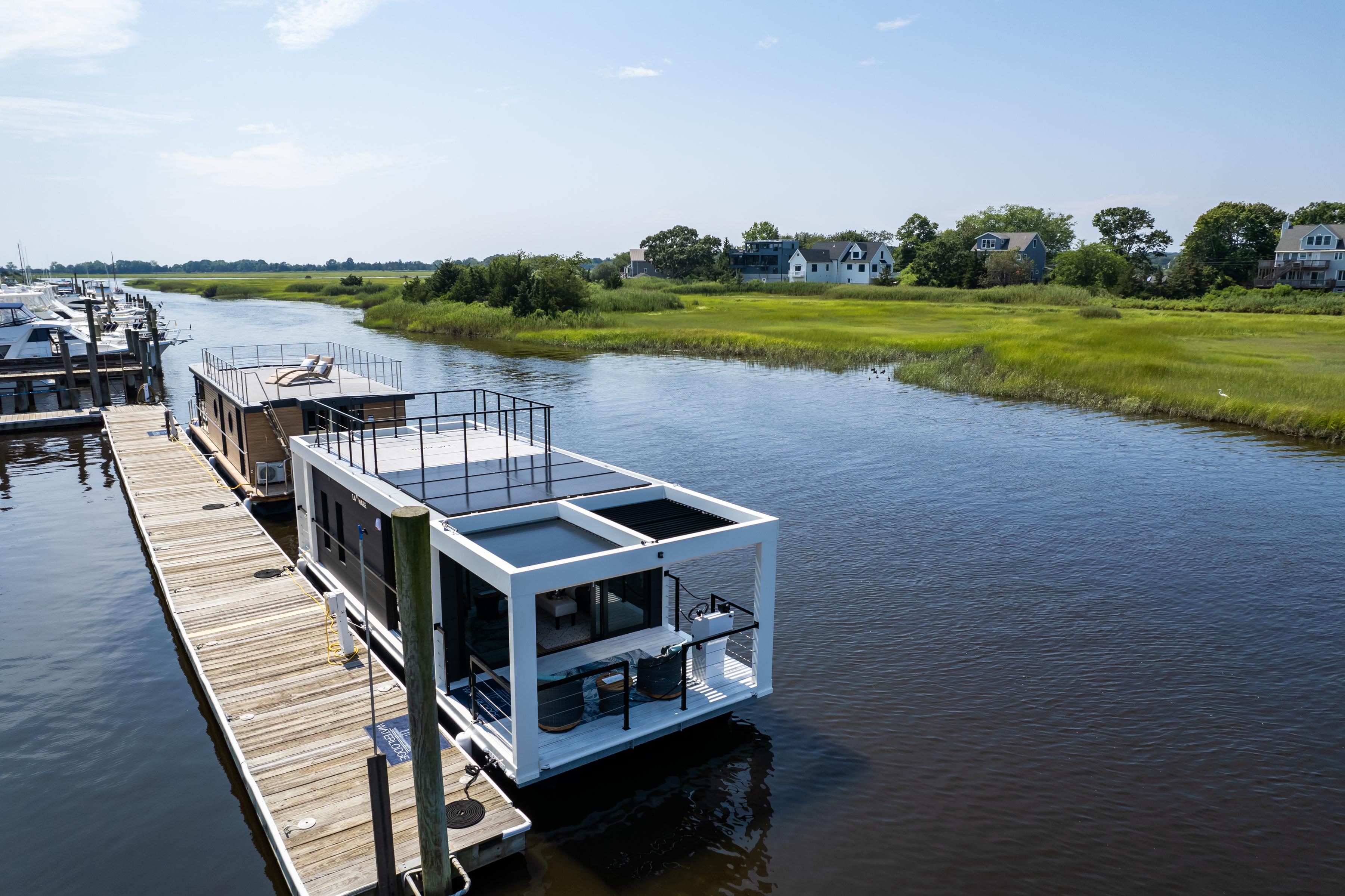 Modern Waterlodge 11 houseboat docked on a serene river, surrounded by lush greenery.