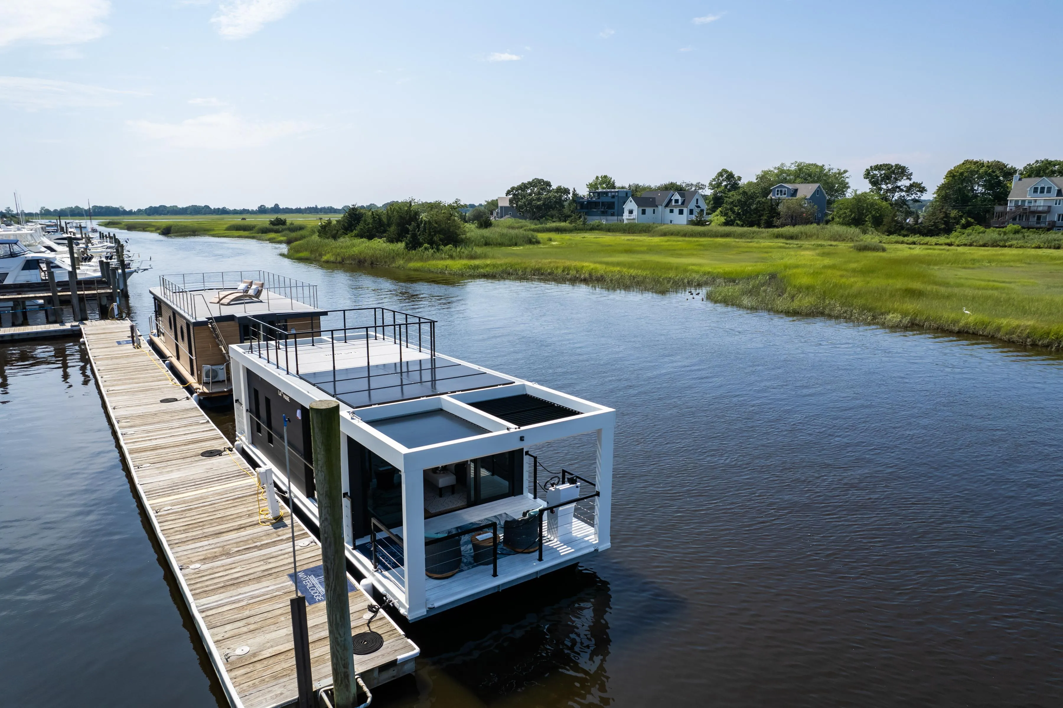 Modern Waterlodge 11 houseboat docked on a serene river, surrounded by lush greenery.