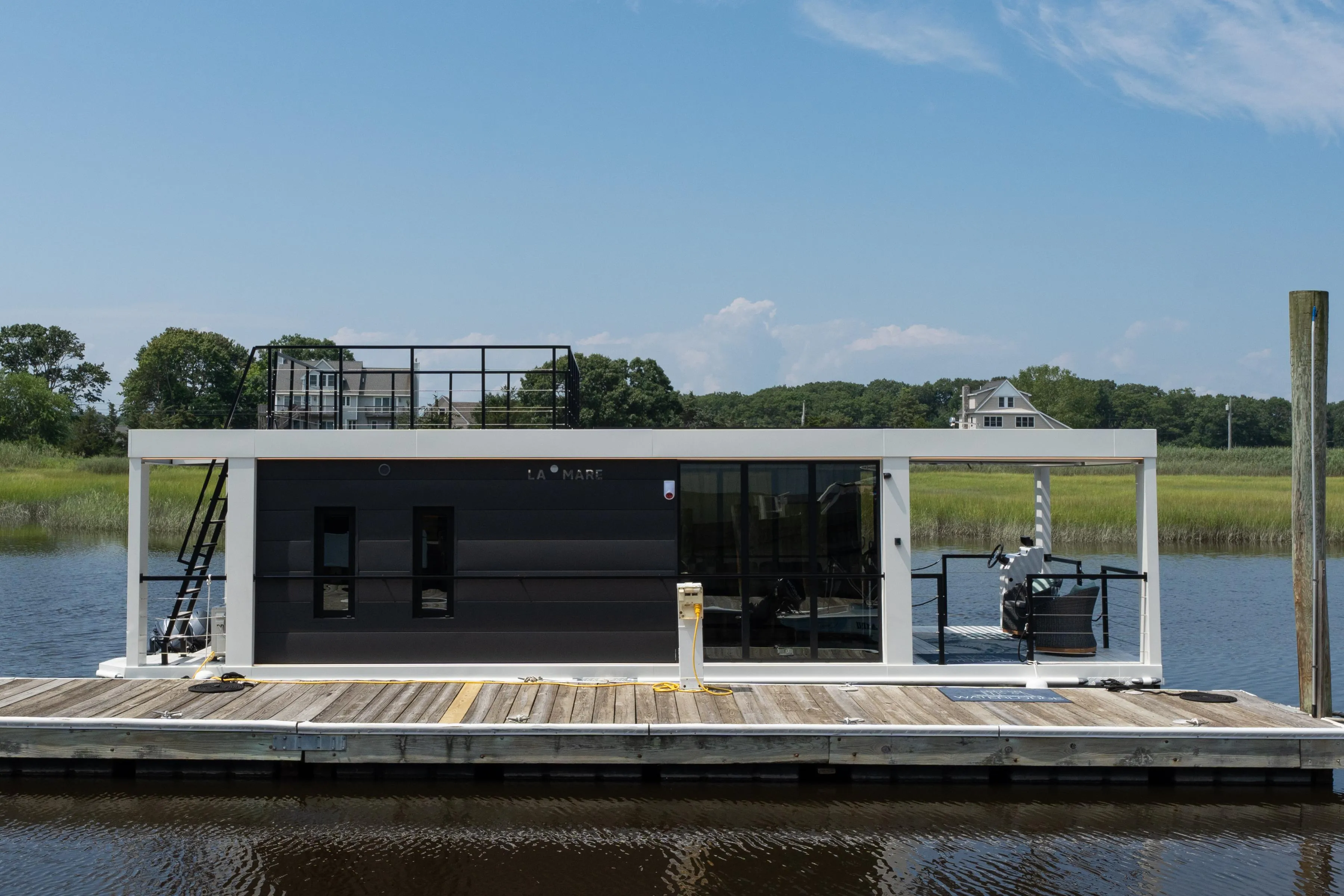 Modern Waterlodge 11 houseboat docked on a serene river, showcasing sleek design and rooftop deck.