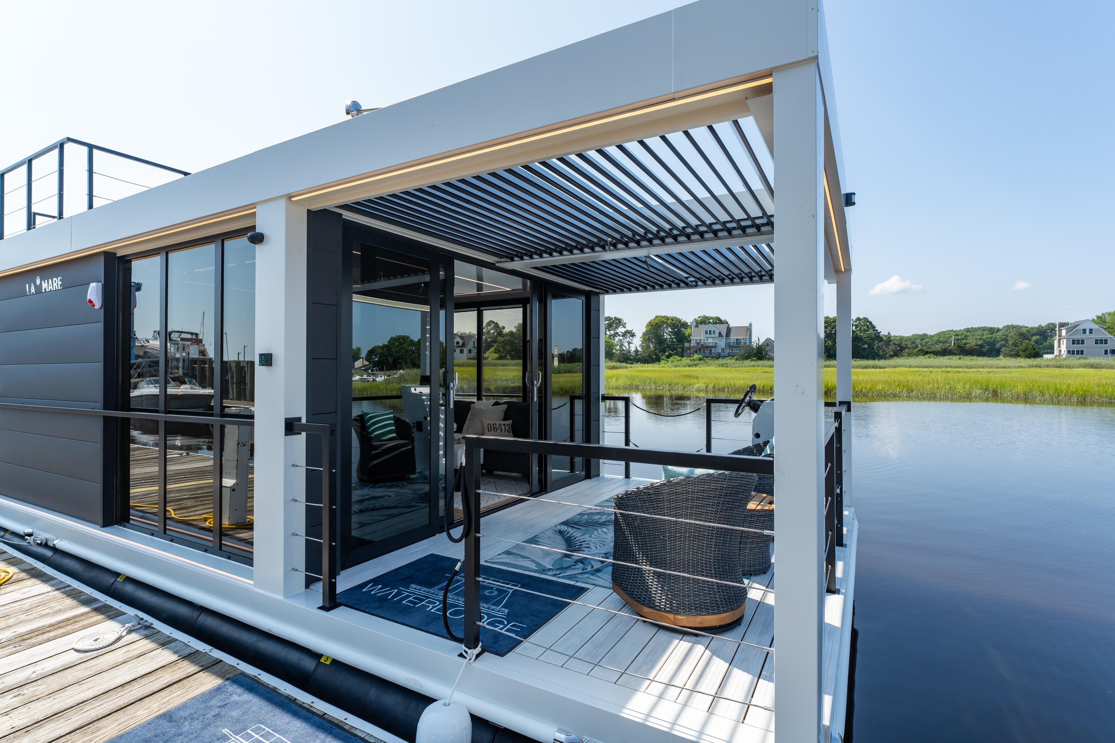 Modern Waterlodge 11 houseboat, 2025 model, with sleek design and outdoor seating on a serene lake.