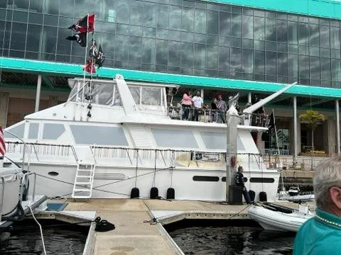 The Jobsite Yacht Photos Pics 1988 Viking Motor Yacht docked with people on deck, flags flying, modern building backdrop.