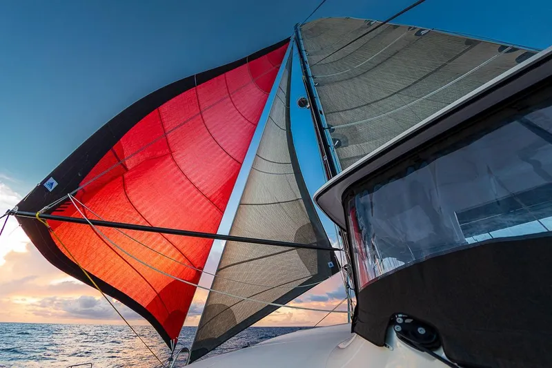  Yacht Photos Pics Sailing on a 2017 Lagoon 52 S catamaran with vibrant red and beige sails at sunset.