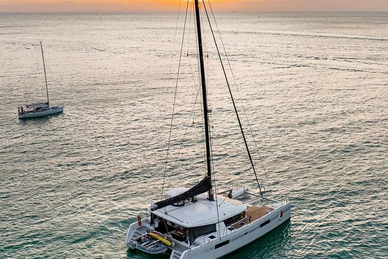  Yacht Photos Pics 2017 Lagoon 52 S catamaran sailing at sunset on calm ocean waters.