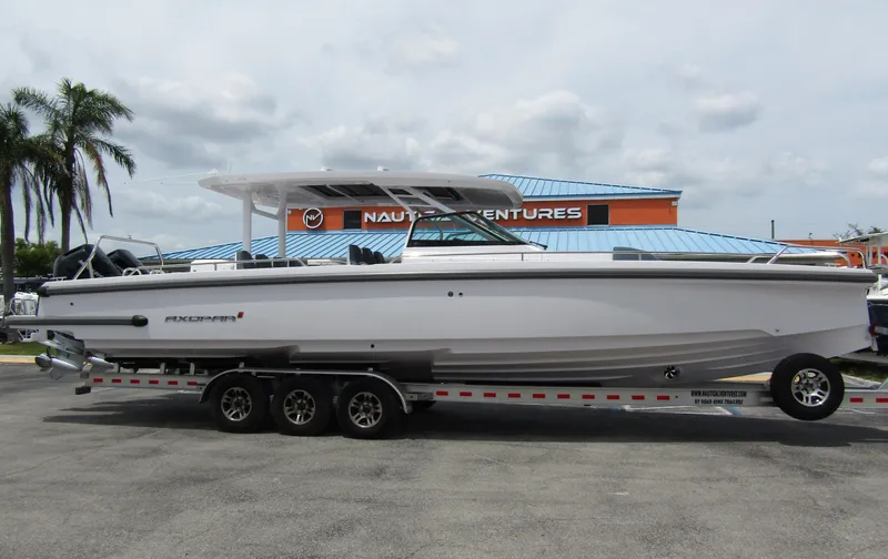  Yacht Photos Pics 2024 Axopar 37 Sun Top boat on a trailer, parked outdoors near palm trees.