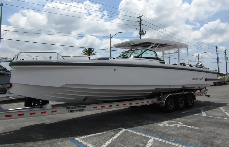  Yacht Photos Pics 2024 Axopar 37 Sun Top boat on trailer under cloudy sky.
