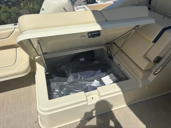  Yacht Photos Pics 2025 Chris-Craft Calypso 32 boat storage compartment with open lid and beige seating.