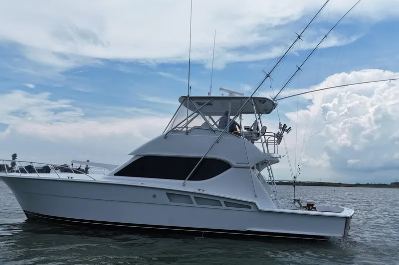 Loca Louise Yacht Photos Pics 2002 Hatteras 50 Convertible Sportfish yacht on calm waters under a cloudy sky.