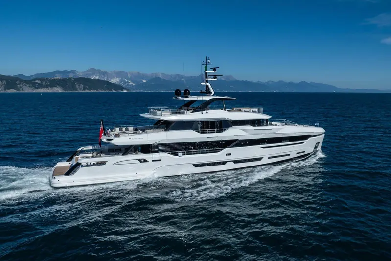  Yacht Photos Pics Luxurious 2025 Baglietto DOM 133 yacht cruising on open sea with scenic mountain backdrop.