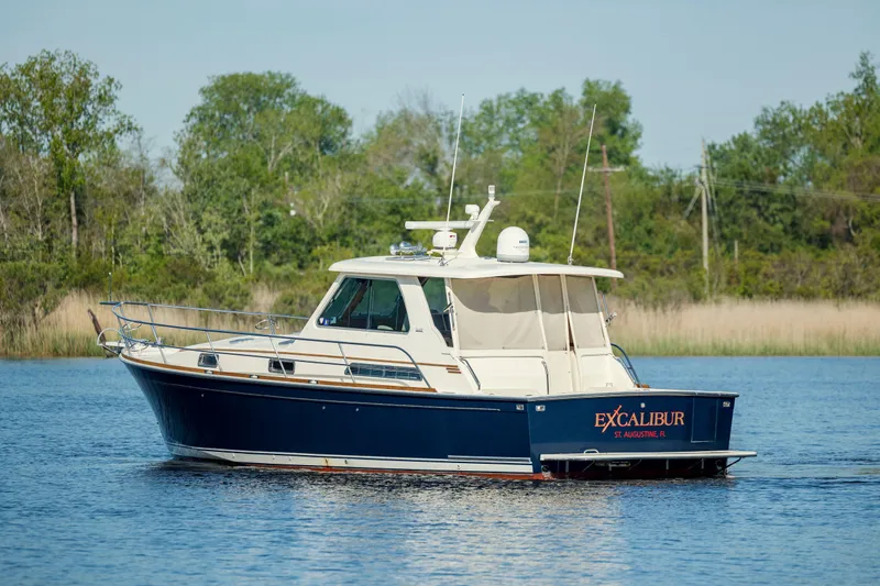  Yacht Photos Pics 2009 Sabre 42 Express boat on calm water, surrounded by lush greenery.