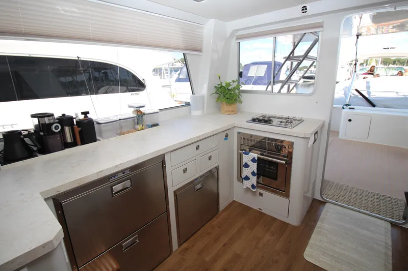 Build To Order Yacht Photos Pics Modern kitchen interior of 2026 Chris White Spindrift 47 yacht with appliances and wooden flooring.