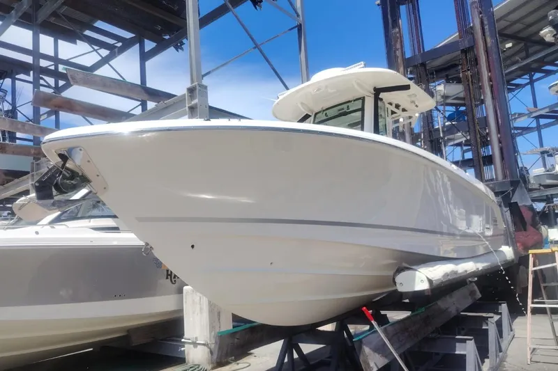  Yacht Photos Pics 2024 Boston Whaler 280 Outrage boat in dry dock, showcasing sleek design and sturdy build.