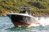 2021 Comitti Isola 33 boat cruising on water near a lush, green shoreline.