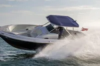 2021 Comitti Isola 33 speedboat cruising on water with a blue canopy.