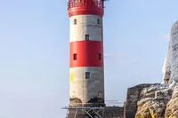 2021 Comitti Isola 33 boat near a red and white lighthouse on a sunny day.