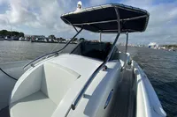 2021 Comitti Isola 33 boat with canopy, docked in a marina under cloudy skies.
