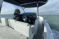 2021 Comitti Isola 33 boat cruising on open water, person steering under canopy.
