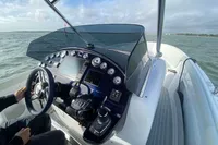 2021 Comitti Isola 33 boat dashboard with steering wheel and control panel on open water.