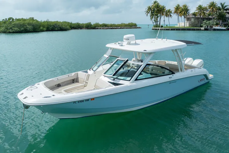  Yacht Photos Pics 2018 Boston Whaler 320 Vantage boat on calm turquoise water, surrounded by lush greenery.