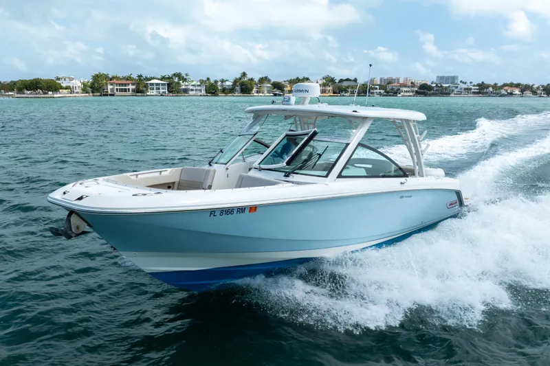  Yacht Photos Pics 2018 Boston Whaler 320 Vantage cruising on open water near coastal homes.