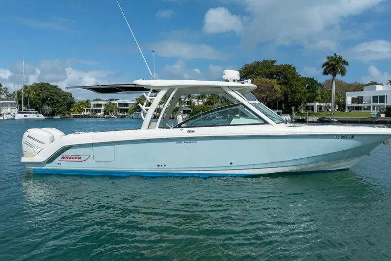  Yacht Photos Pics 2018 Boston Whaler 320 Vantage boat on calm water, with modern waterfront homes in the background.