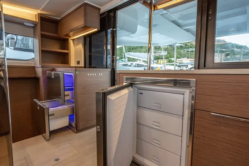 Clearlake III Yacht Photos Pics Modern kitchen interior of 2021 Lagoon 46 yacht with open fridge and sleek wood cabinetry.