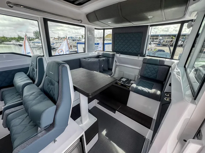  Yacht Photos Pics 2024 Axopar 37XC CROSS CABIN interior with modern seating and table, docked at marina.