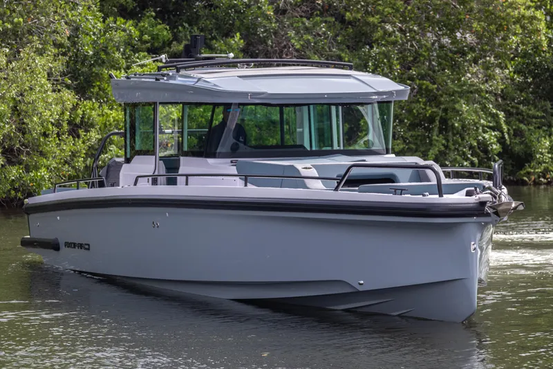  Yacht Photos Pics 2024 Axopar 37XC CROSS CABIN boat on a calm waterway, surrounded by lush greenery.