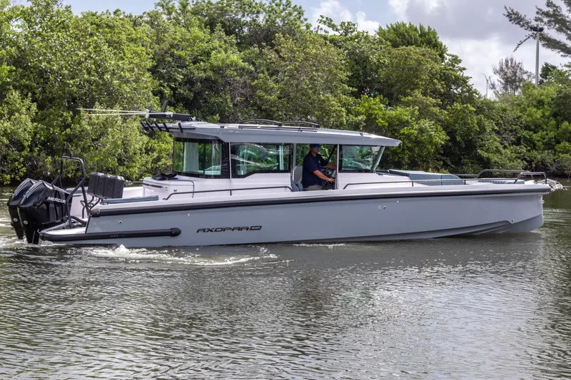  Yacht Photos Pics 2024 Axopar 37XC CROSS CABIN cruising on a serene waterway, surrounded by lush greenery.