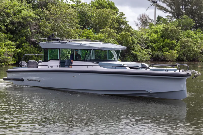  Yacht Photos Pics 2024 Axopar 37XC CROSS CABIN cruising on a calm river, surrounded by lush greenery.