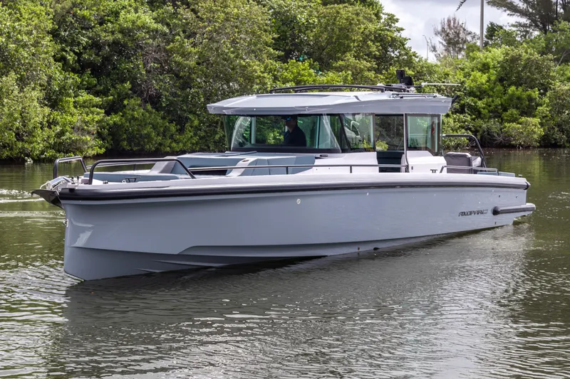  Yacht Photos Pics 2024 Axopar 37XC CROSS CABIN boat cruising on a calm river surrounded by lush greenery.